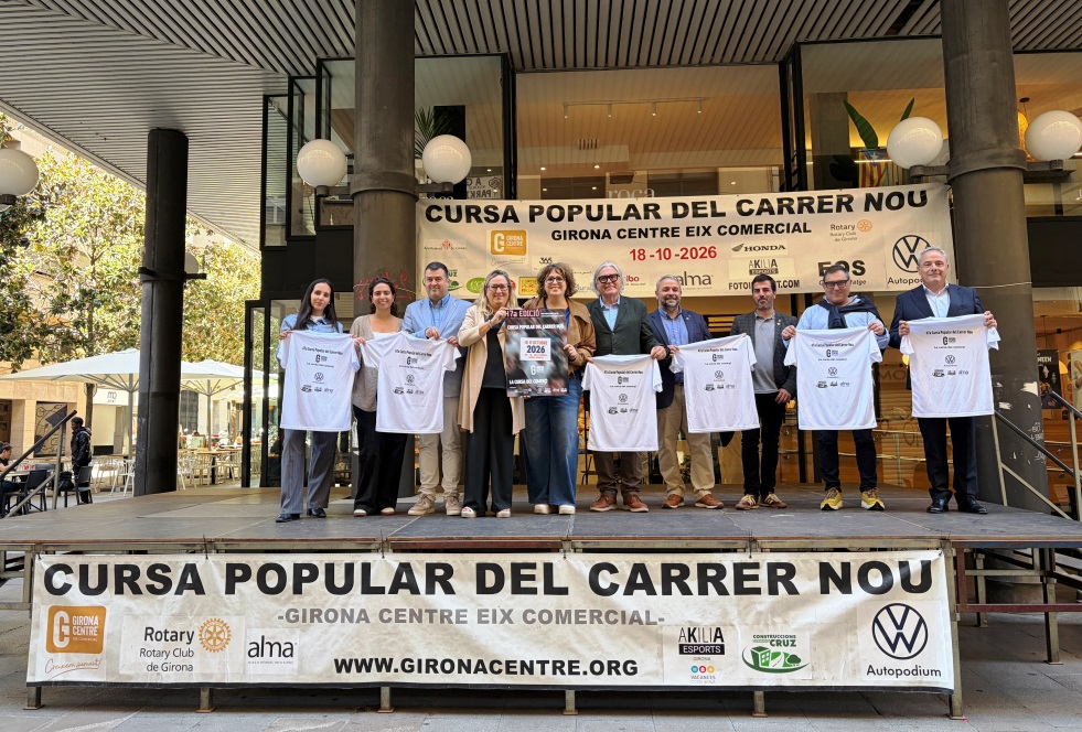 Grup mostrant les samarretes i el cartell de l'edició a sobre d'una tarima