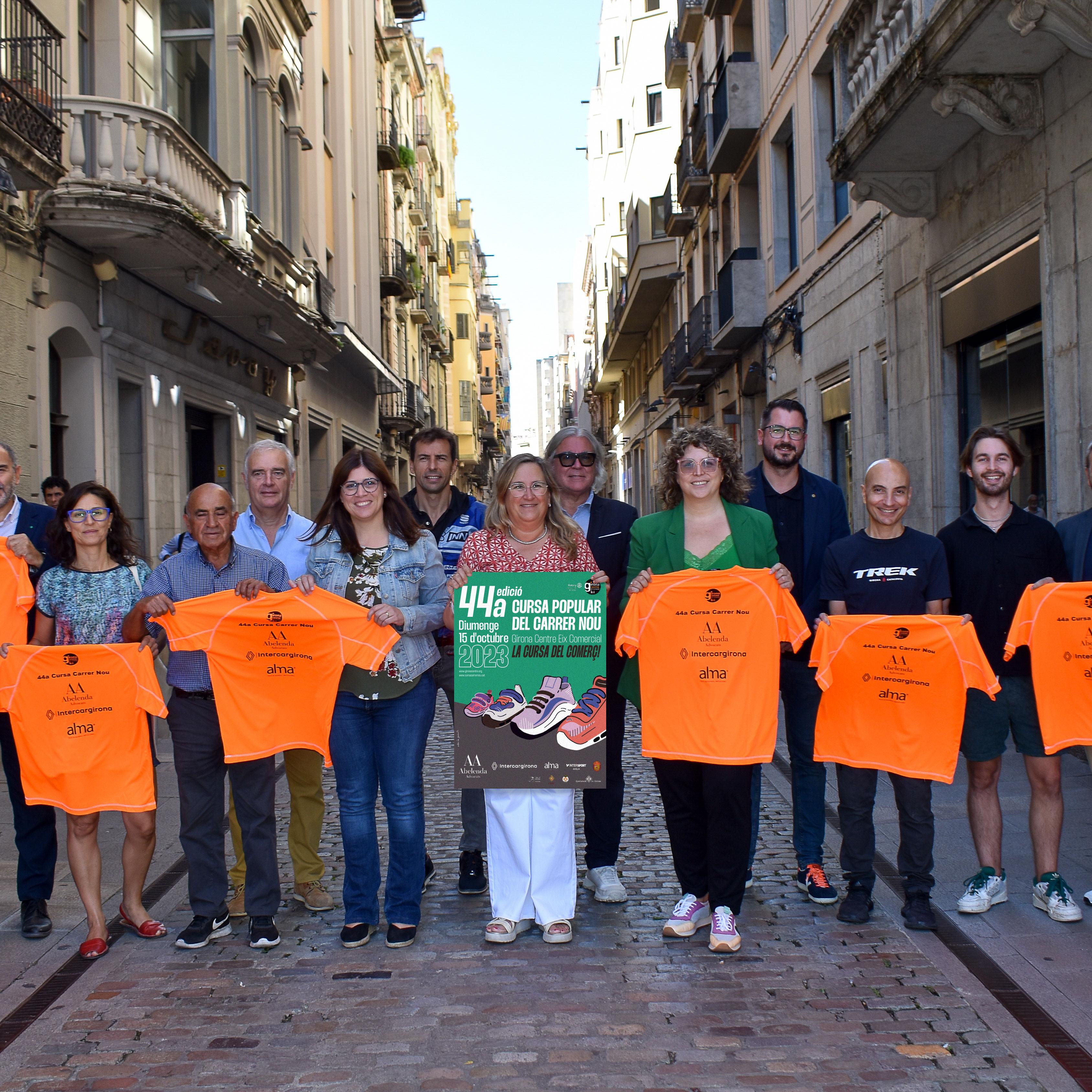 Organitzadors i col·laboradors de la cursa mostren al carrer el cartell i la samarreta 2023