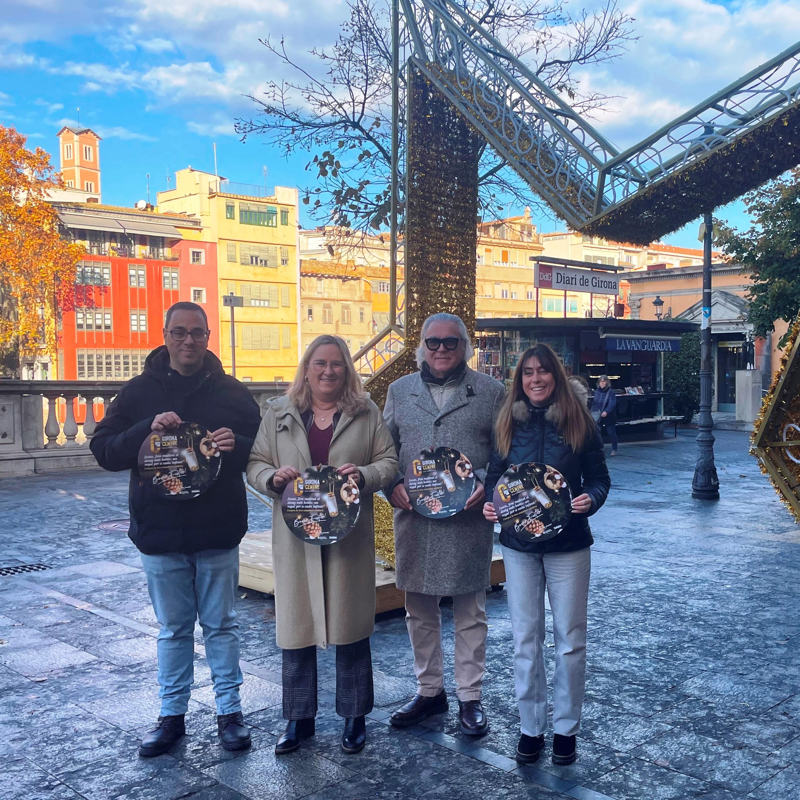 Membres de la Junta de Govern de Girona Centre amb el cartell de campanya “Junts fem realitat el desig més bonic, un regal per a cada infant”, a l’inici de la Rambla de la ciutat.