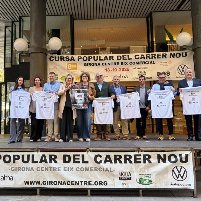 Grup mostrant les samarretes i el cartell de l'edició a sobre d'una tarima