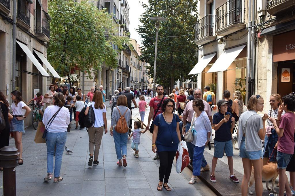 gent passejant per un carrer comercial