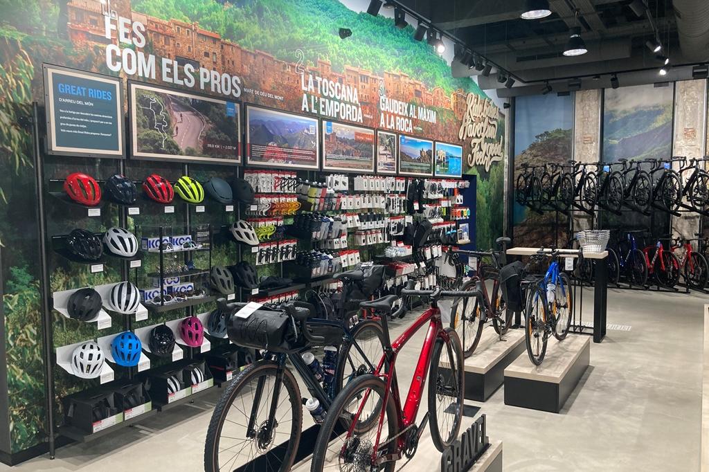 Espai de la botiga amb bicicletes al davant i al fons, i productes per als ciclistes a l'esquerra