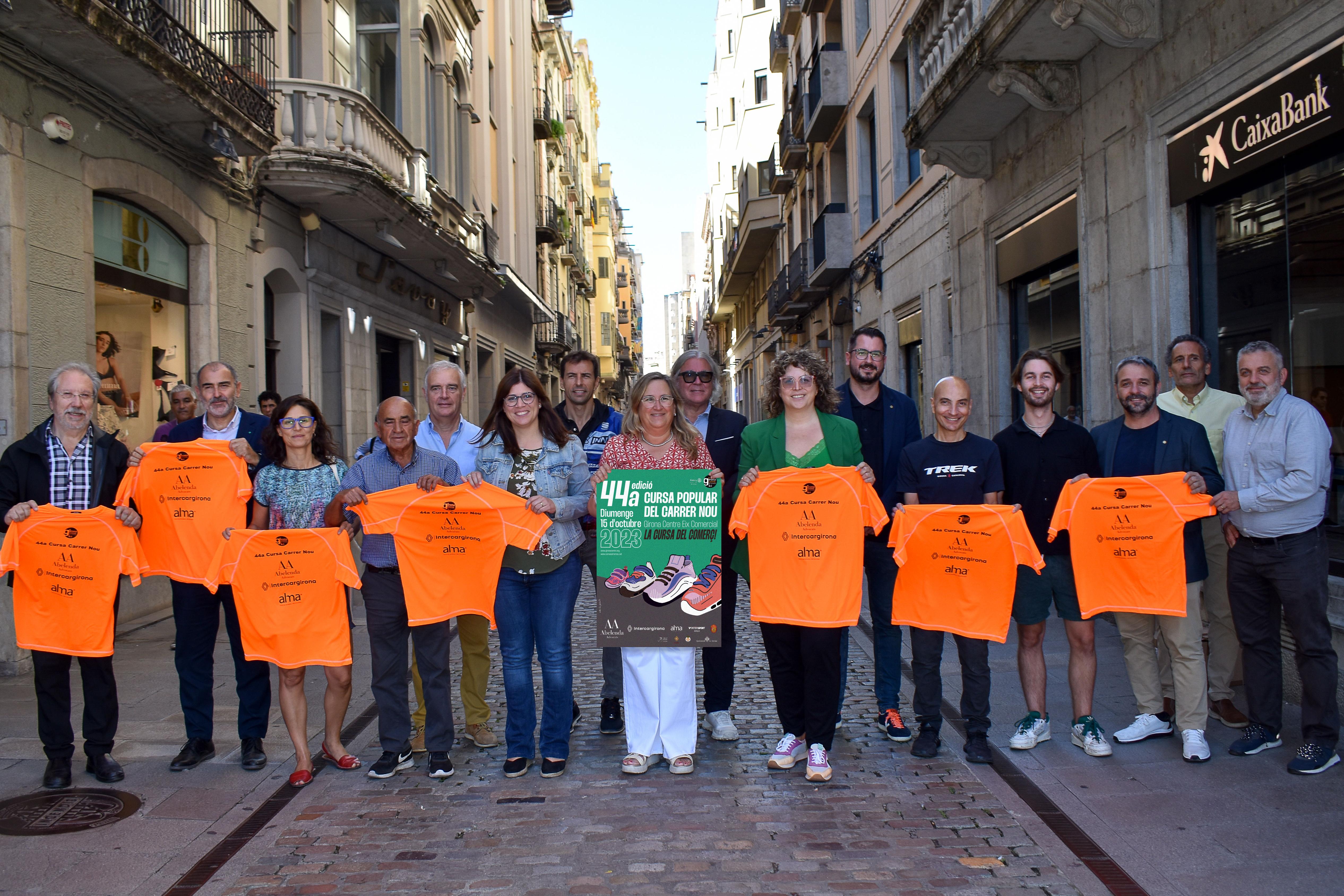 Organitzadors i col·laboradors de la cursa mostren al carrer el cartell i la samarreta 2023