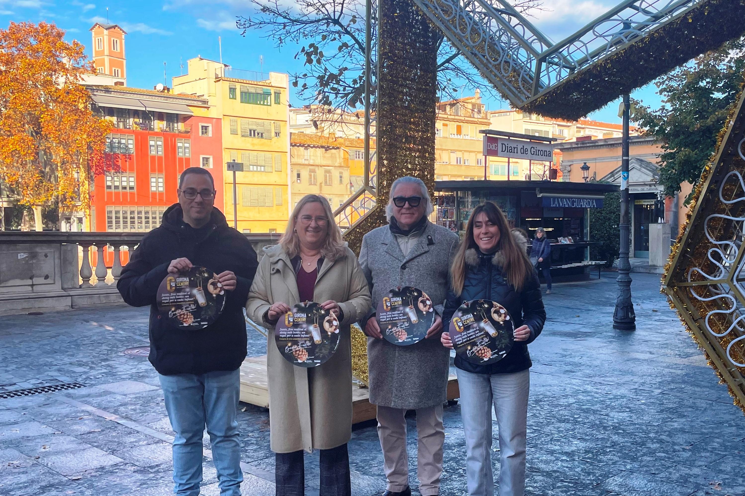 Membres de la Junta de Govern de Girona Centre amb el cartell de campanya “Junts fem realitat el desig més bonic, un regal per a cada infant”, a l’inici de la Rambla de la ciutat.