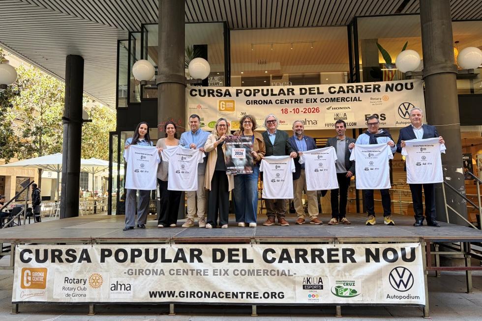 Grup mostrant les samarretes i el cartell de l'edició a sobre d'una tarima