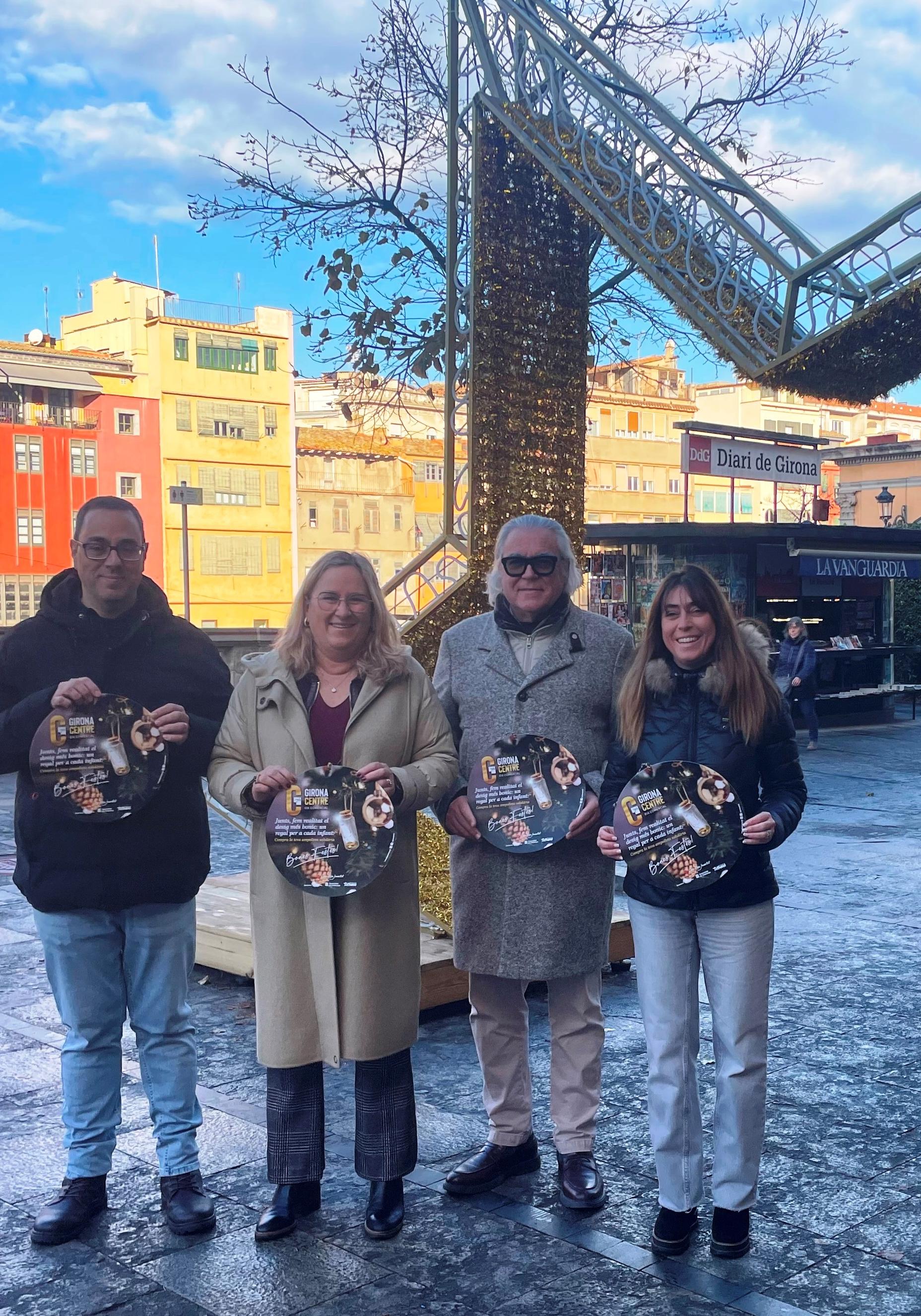 Membres de la Junta de Govern de Girona Centre amb el cartell de campanya “Junts fem realitat el desig més bonic, un regal per a cada infant”, a l’inici de la Rambla de la ciutat.