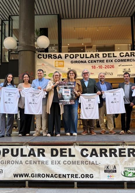 Grup mostrant les samarretes i el cartell de l'edició a sobre d'una tarima