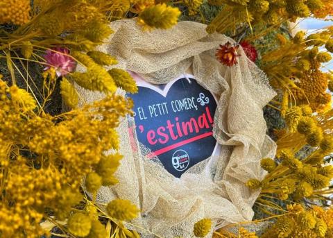 Coixi fet de flors grogues. Al mig s'hi pot llegir "El petit comerç t'estima"